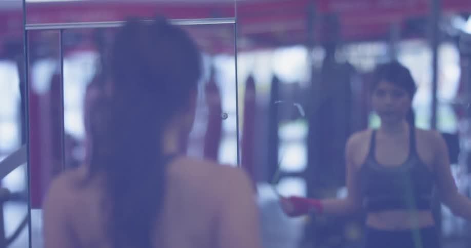Woman is jumping rope in gym during the day
