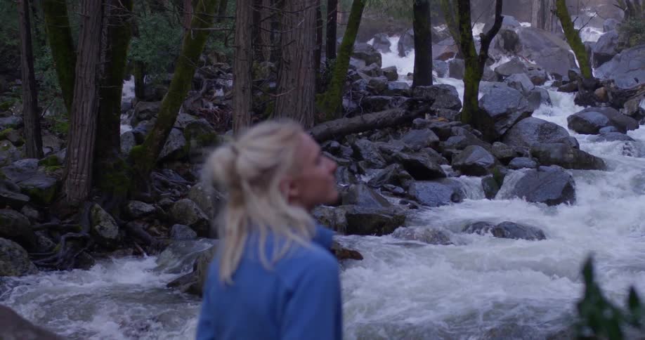 A woman stands by the flowing rapids