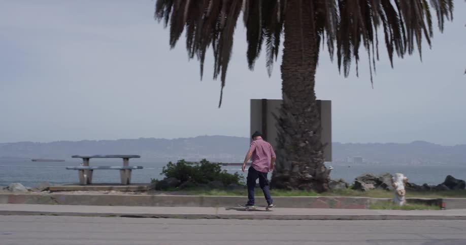 A man skateboards on a sidewalk