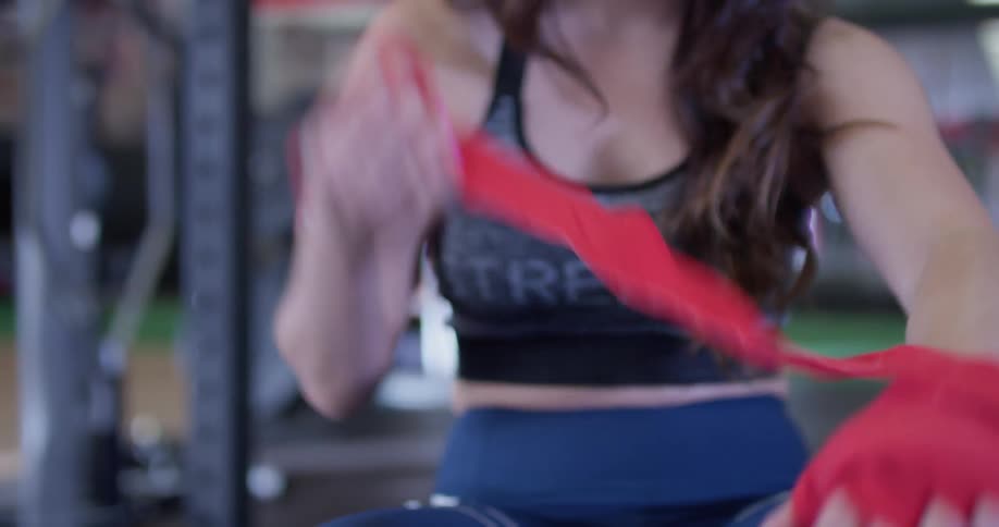 A woman wraps athletic tape around her hand in a gym