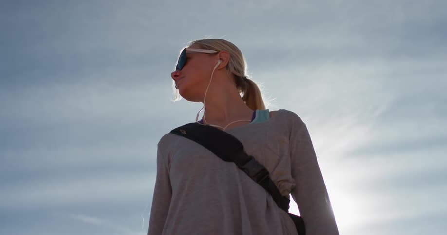 A woman wears headphones outside on a sunny day