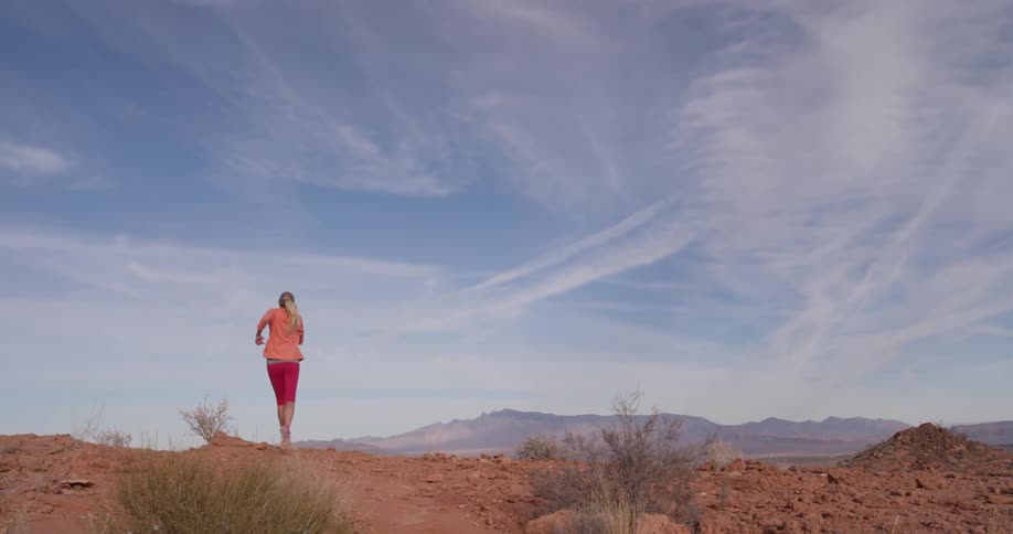A woman runs up the rocks on the hill