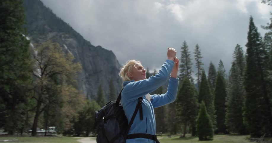 A woman takes a photograph of the forest with her phone