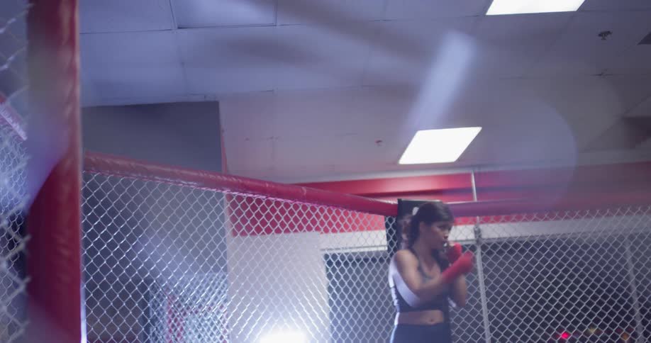 Woman practices punching in a fenced in area in a gym