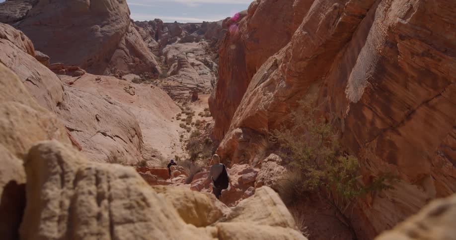 A woman is hiking through a ravine in a desert setting in daylight