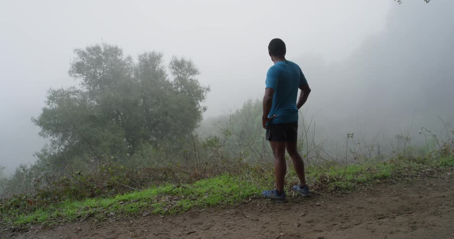 A jogger stops and looks over the hill