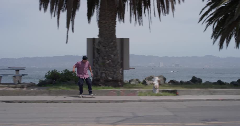 Man wearing a toque rides a skateboard near the ocean