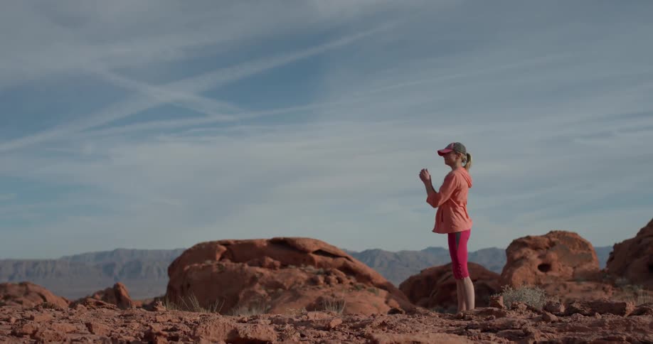 A woman is stretching and twisting as she stands in the desert