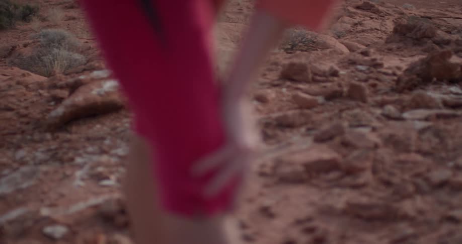 A woman bends over to catch her breath in a desert