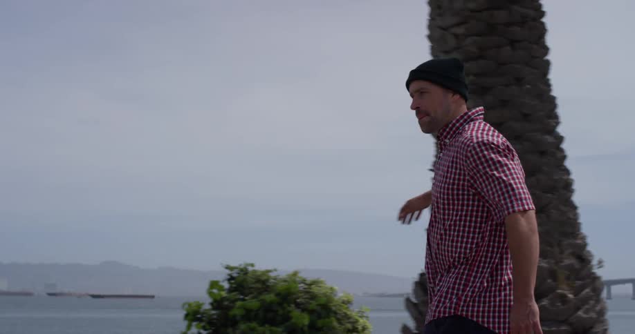 Man wearing a toque pushes himself along a path near the water