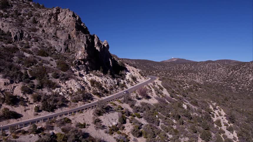 A car is driving on a road through a desert landscape on a sunny day