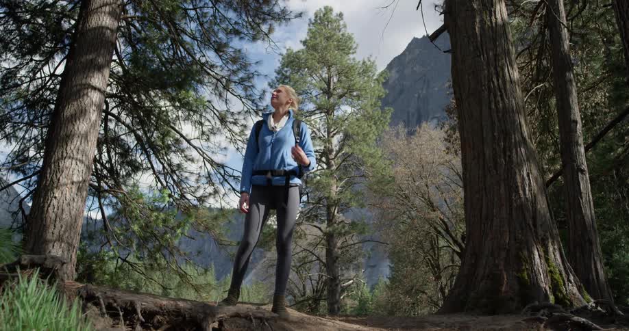 The woman is looking around the forest on the hill