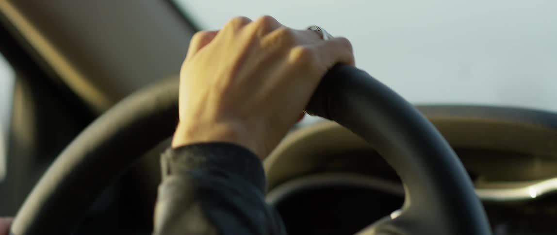 A woman drives a car on a cloudy day