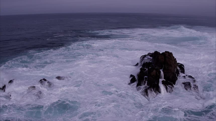 The waves crash against the tall rocks