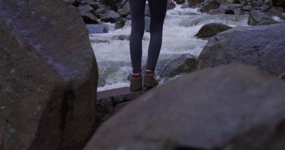 A woman stands on the rocks in the stream