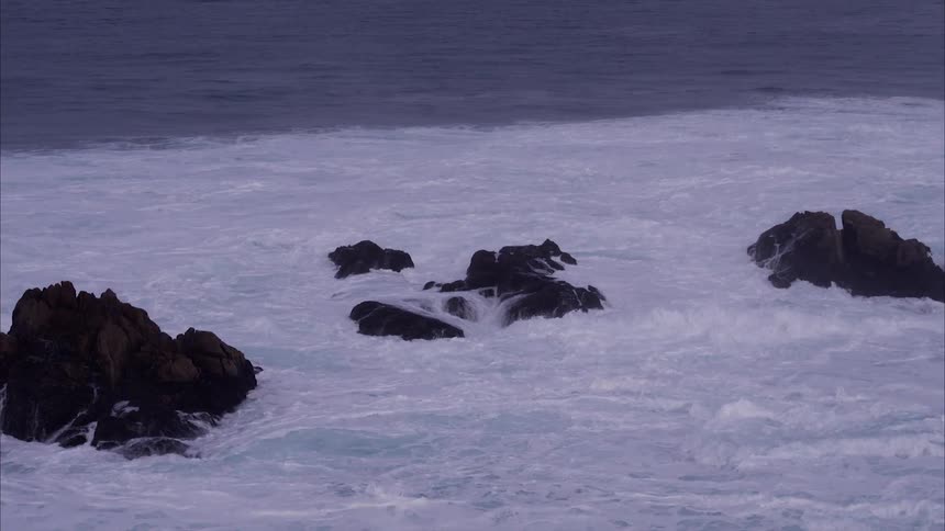 Waves crash over the rock formations near the shore