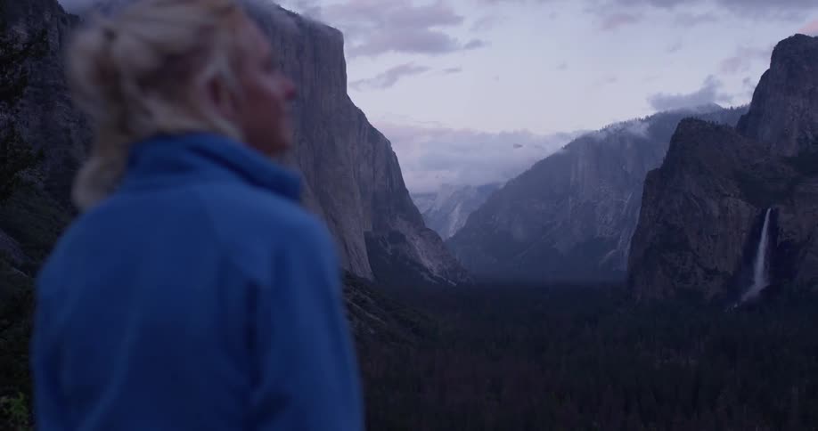 Woman looks out over rocky hilly terrain at sunset