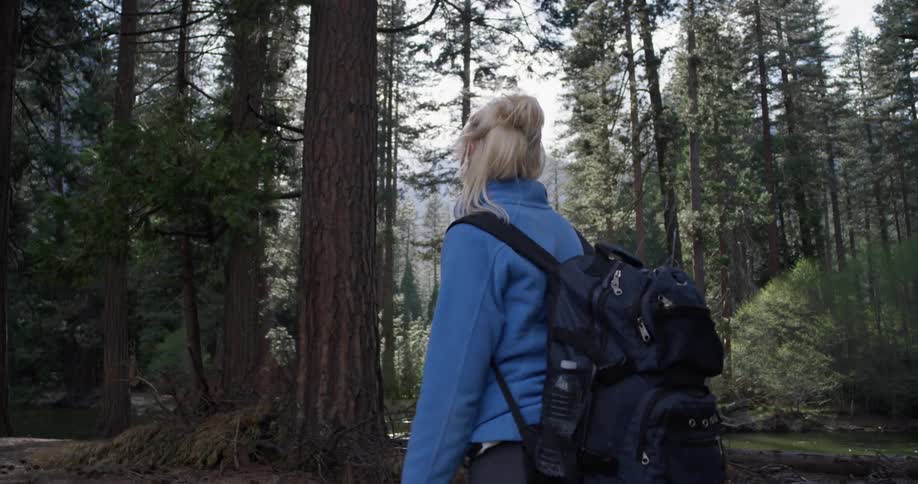 Woman is hiking near river in the woods