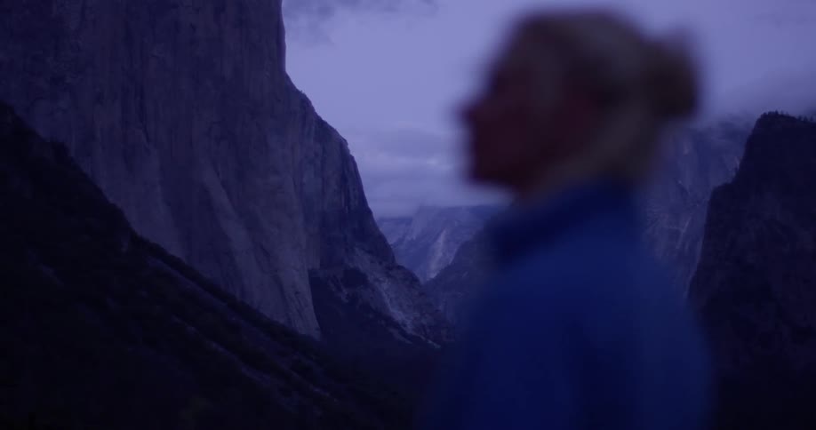 A woman hikes in mountains at dusk