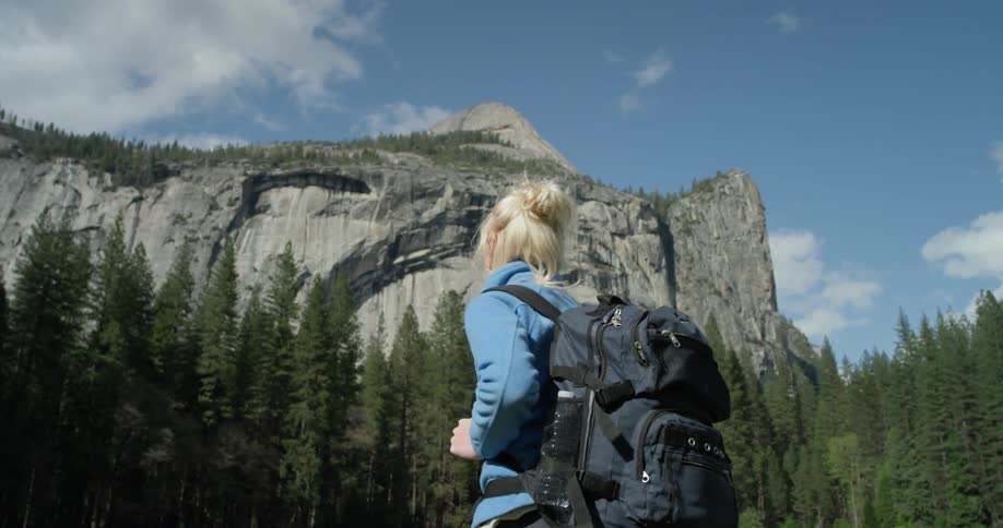 A woman hikes towards the mountains