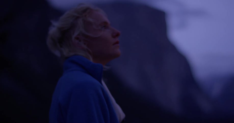 Woman stands outside looking around in the evening