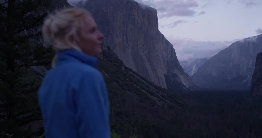 A woman looks out over the mountains at the top