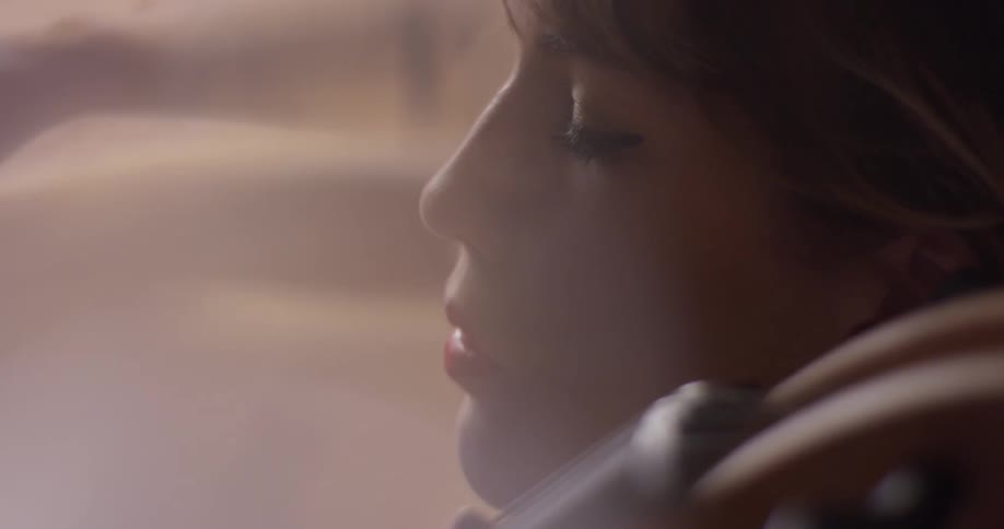 A woman plays a cello with her eyes closed