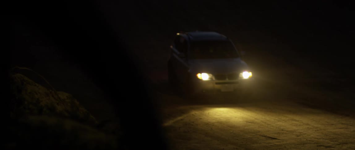 A car travels in the dark with its headlights on