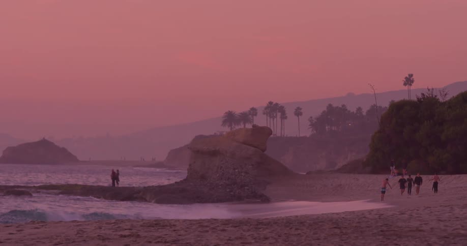 People walk on the beach as the waves roll in