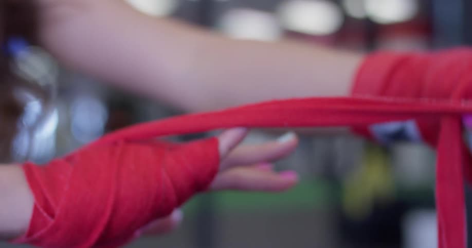 A woman wraps athletic tape around her hand in a gym