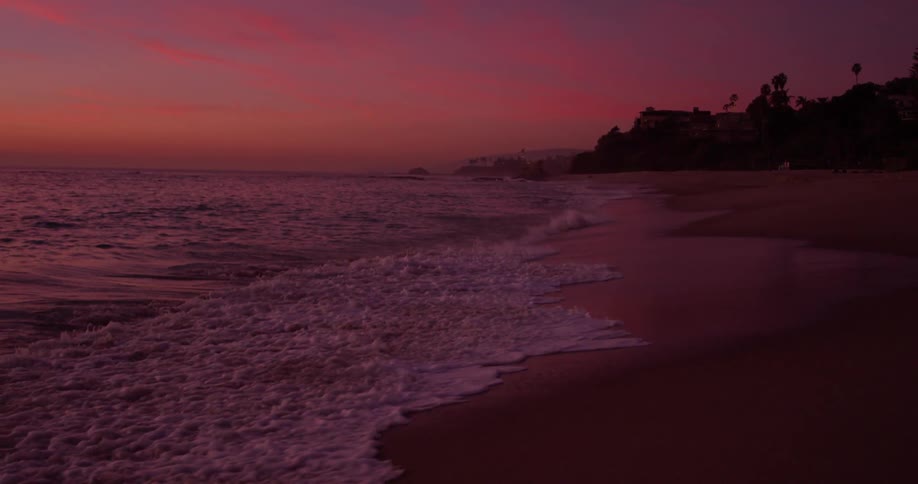 Ocean waves are crashing onto beach after sunset