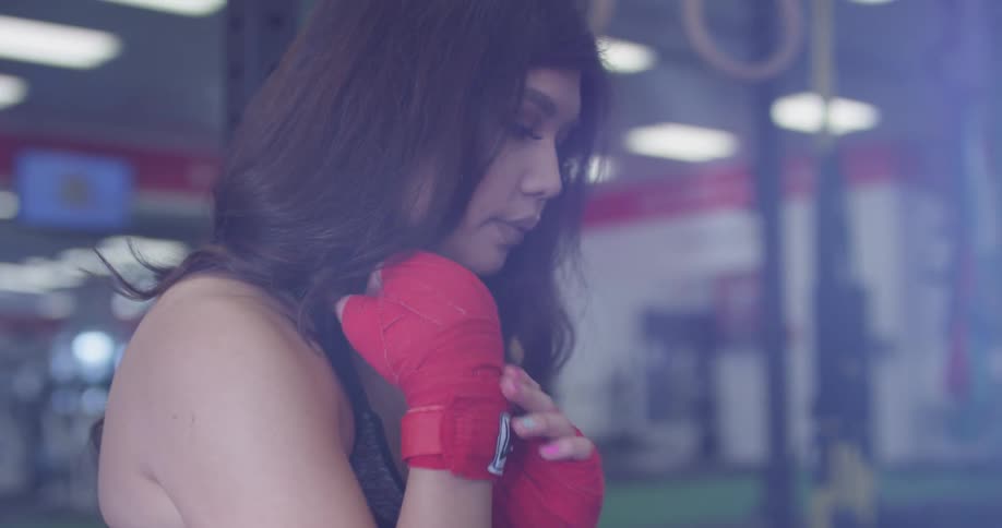 A woman wraps her hands with red tape