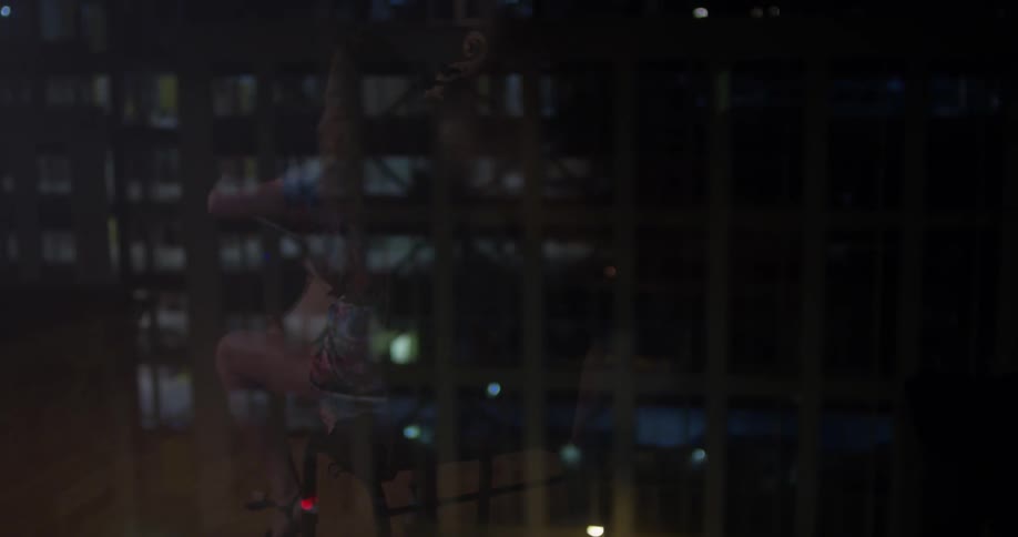A woman plays a cello in a city at night