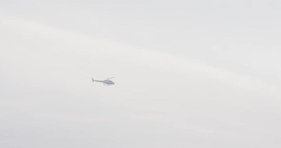 A helicopter flies in a cloudy sky