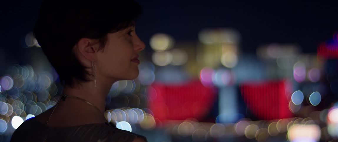 A woman is watching the city at night