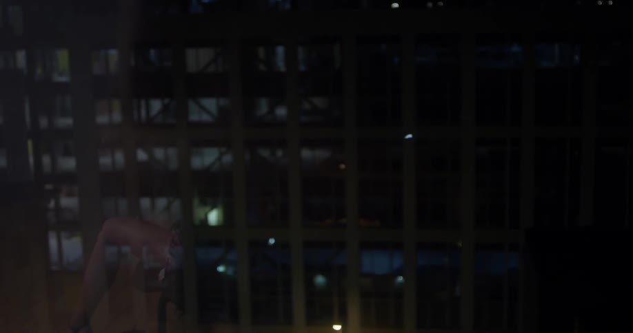 A woman plays a cello in a city at night