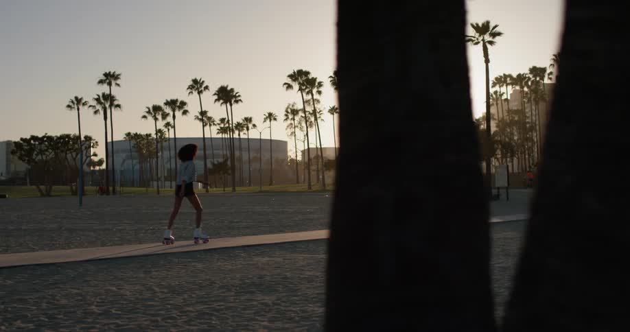 The woman roller skates towards the city at sunset