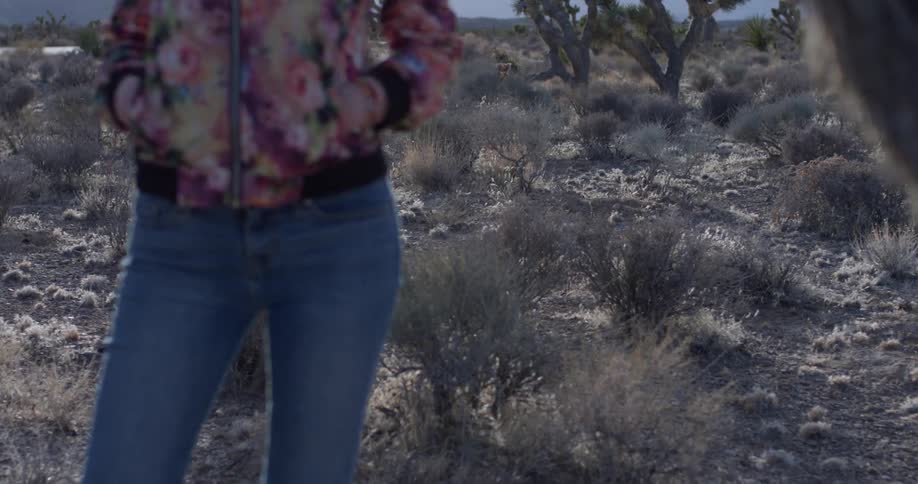 Person stands with their hands in their pockets in the desert on a sunny day