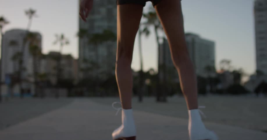 Woman roller skates towards the city in the evening