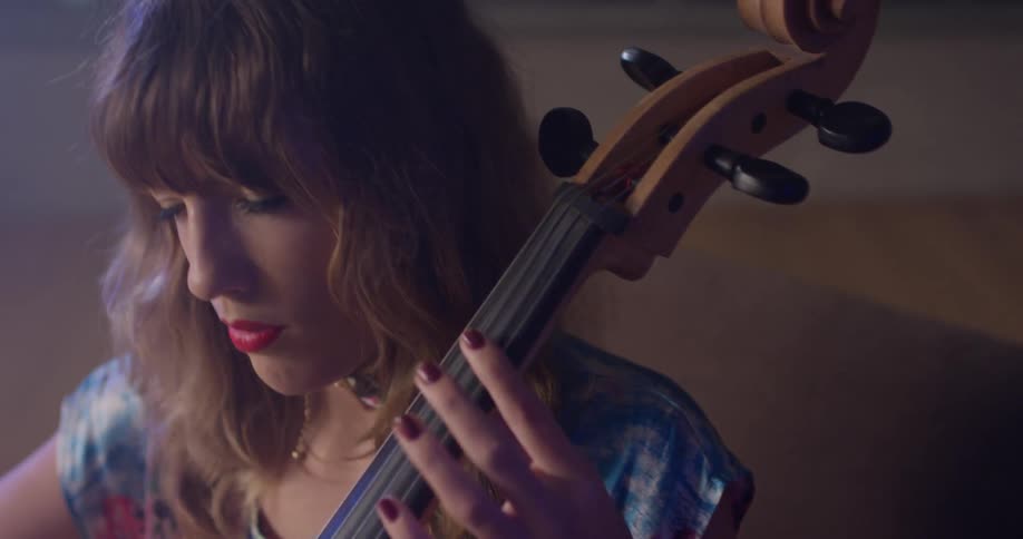 A woman plays a cello with her eyes closed