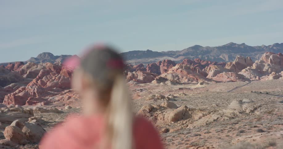 Woman looks out over rocky hilly terrain