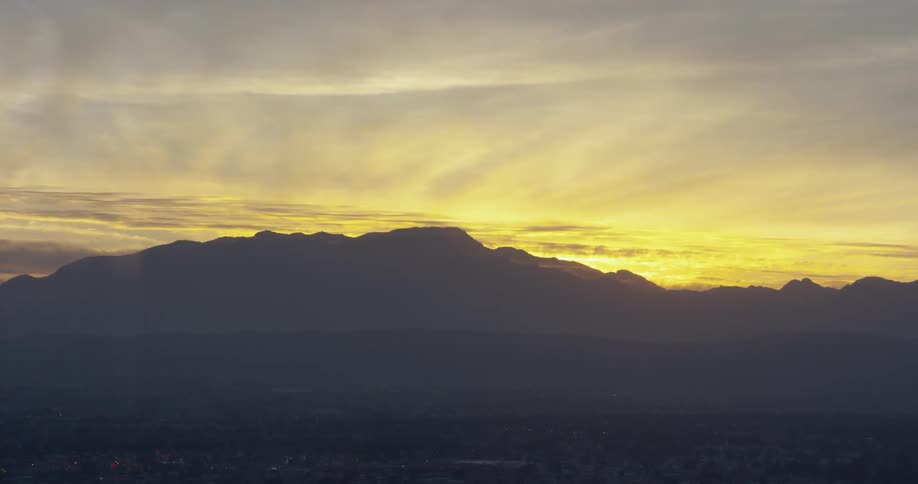 The sun sets behind a mountain