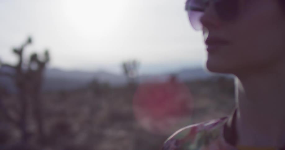 Woman wearing sunglasses stands in a field of vegetation