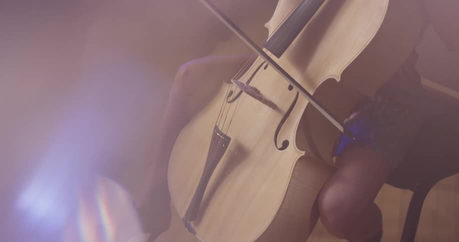 A person sits and plays the double bass in the room