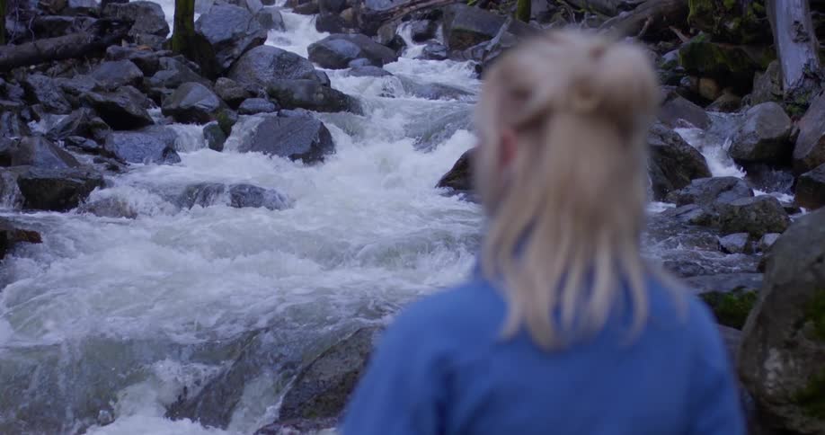 Woman is standing and watching water flow in river