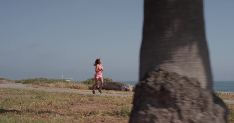 A woman jogs on the path near the beach