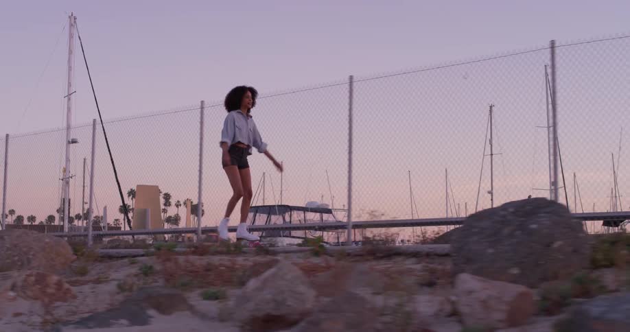 A woman skates on a beach at sunset