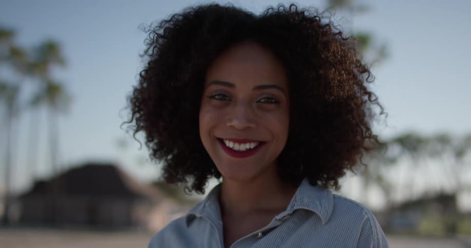 Smiling woman stands outside in the sunlight
