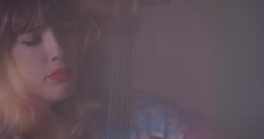A woman plays a cello with her eyes closed