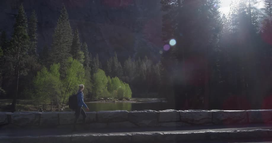 A woman is hiking on the bridge over the river